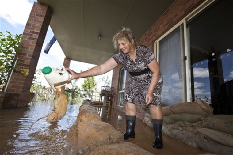 Lorraine Lucic uses a jug to scoop water that is trickling through the sand bags protecting her house from rising flood waters near Euchca, Australia on Jan. 18. Up to 1,500 homes in Kerang, in the north of Victoria state, could be affected if the Lodden River rises any further. 